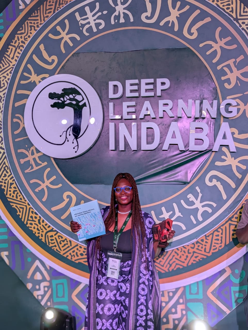 Flora Oladipupo in front of the Deep Learning Indaba 2026 backdrop with her award